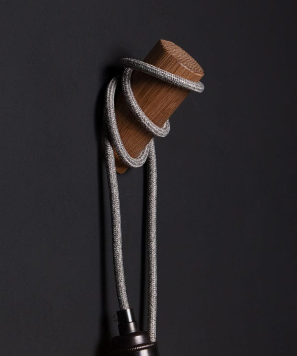 closeup of peg wall light danish oil with grey jumper cable on black wall